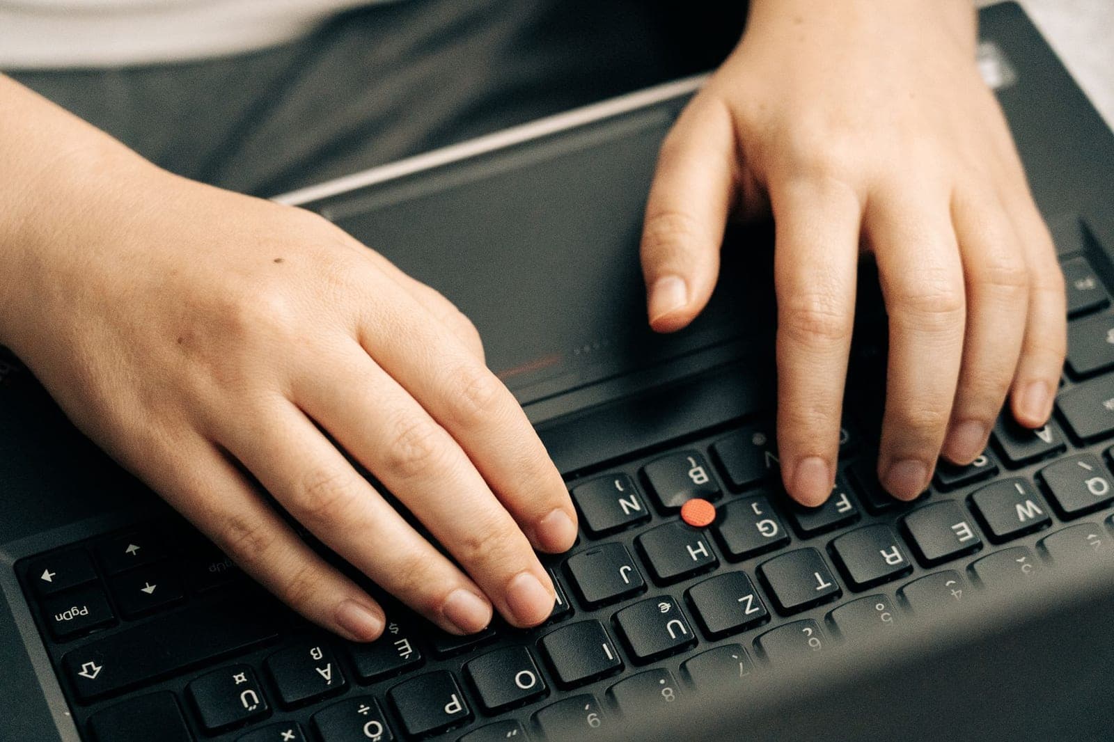 Close-up of hands typing on a black laptop keyboard