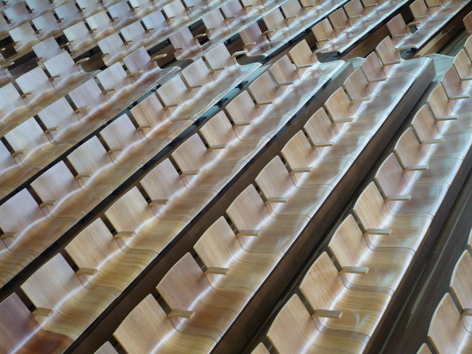 Rows of empty wooden seats in a modern auditorium