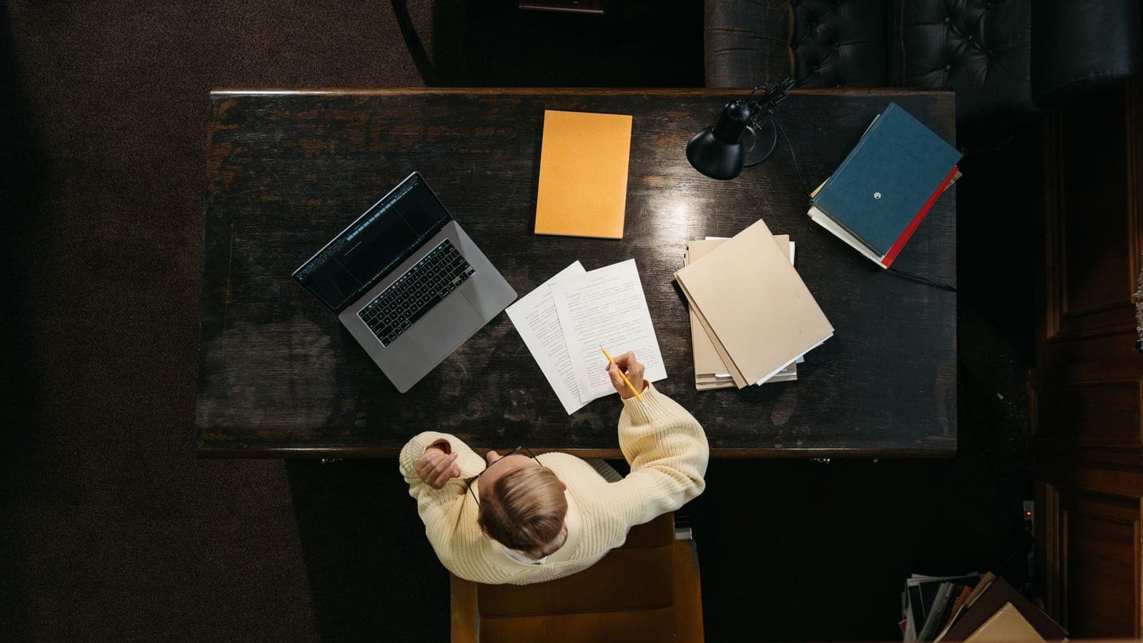 Overhead view of a person working at a desk with a laptop, folders and documents
