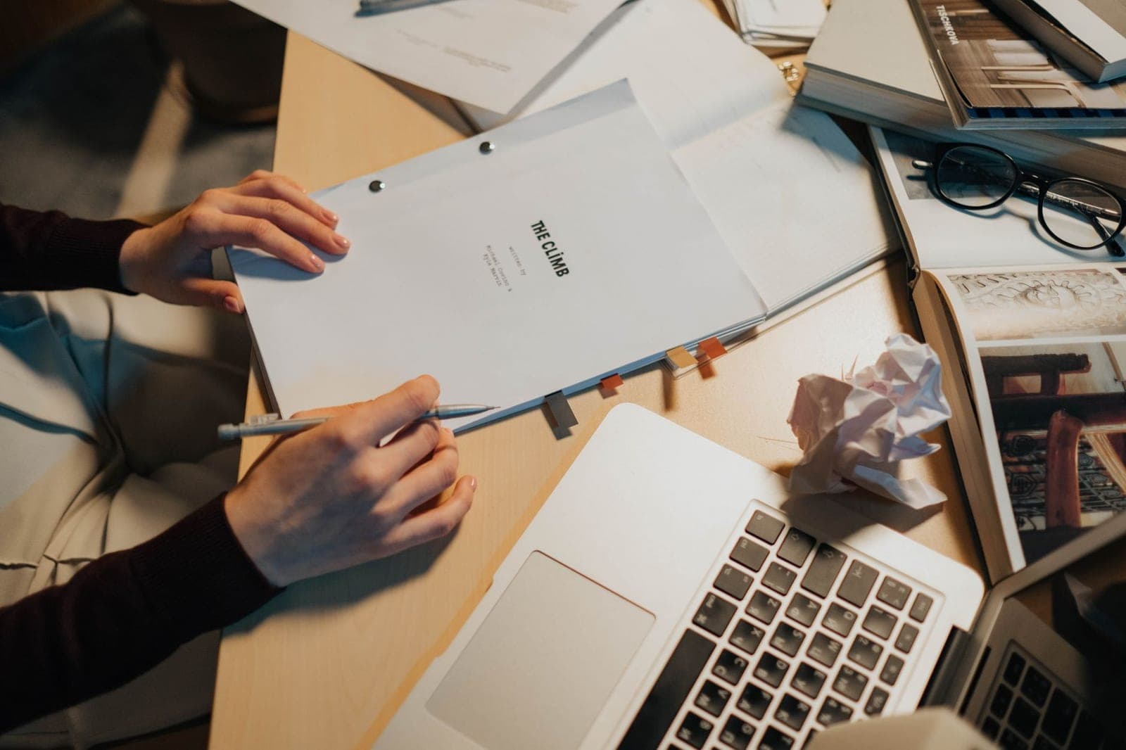 A wooden desk with a printed screenplay, a pen and a mug beside it